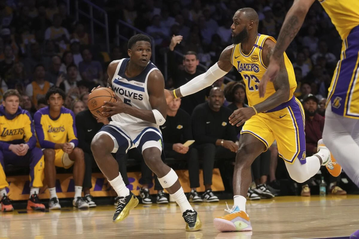 Timberwolves' Anthony Edwards works toward the basket as Lakers' LeBron James defends him during a basketball game.