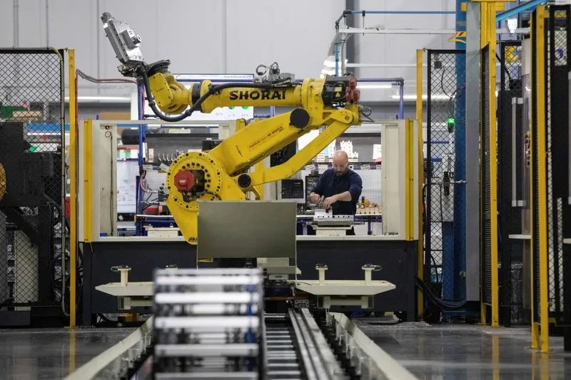 A factory worker at Abipa Canada navigates the challenges of tariff uncertainty alongside automated technology, as captured by Reuters, highlighting the human impact of trade policies on Canada's services sector.