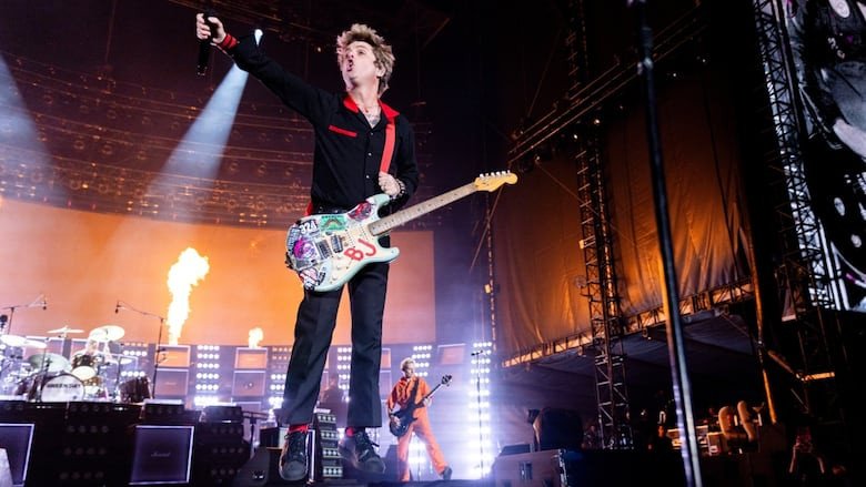 A rock band lead guitarist jumps during a concert.