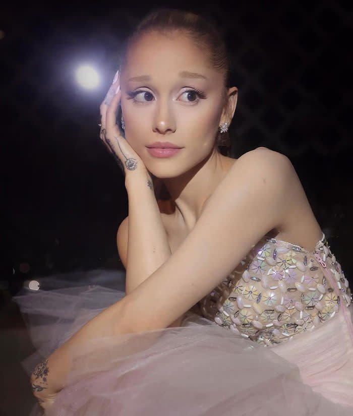 Ariana Grande in a sparkling dress looking concerned at an event, highlighting extremely thin appearance.