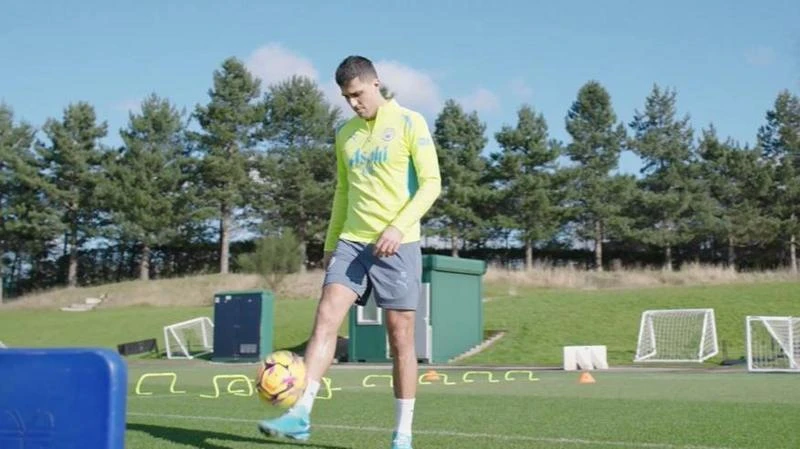 Rodri in training kit, kicking a football