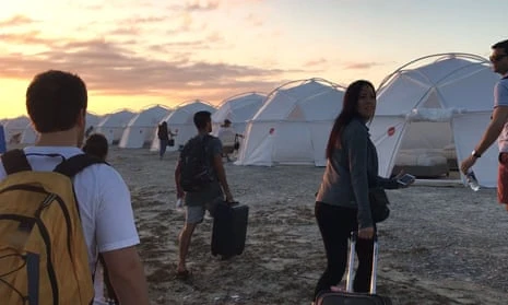 People walk toward tents set up on a beach.