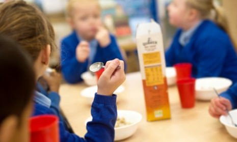 Infants in school uniform eating breakfast