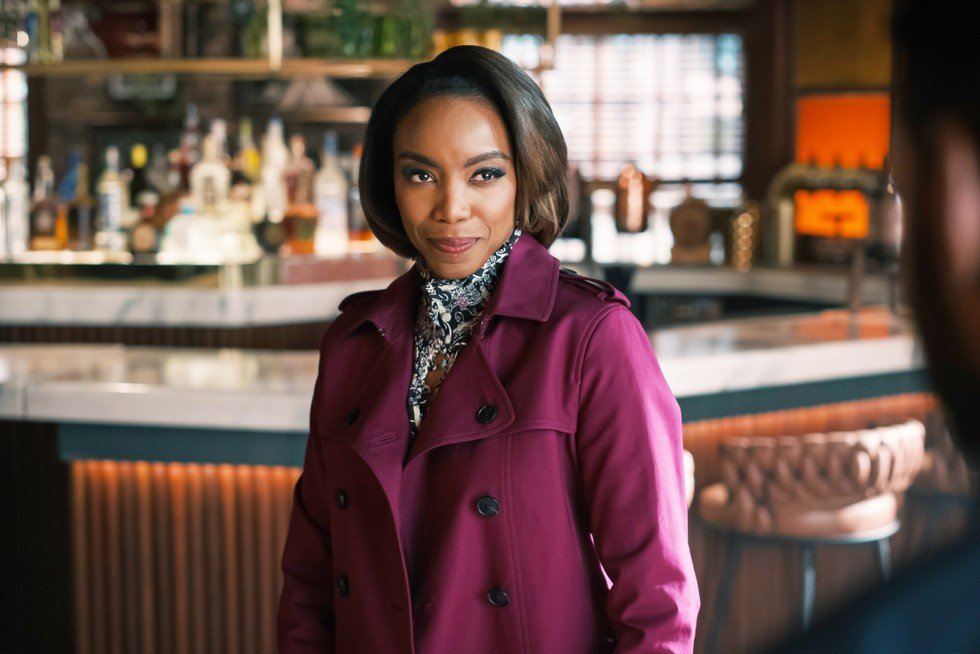 Heather Headley as Helen Decatur, standing in the middle of the restaurant, wearing a purple coat, looking longingly at Erik,