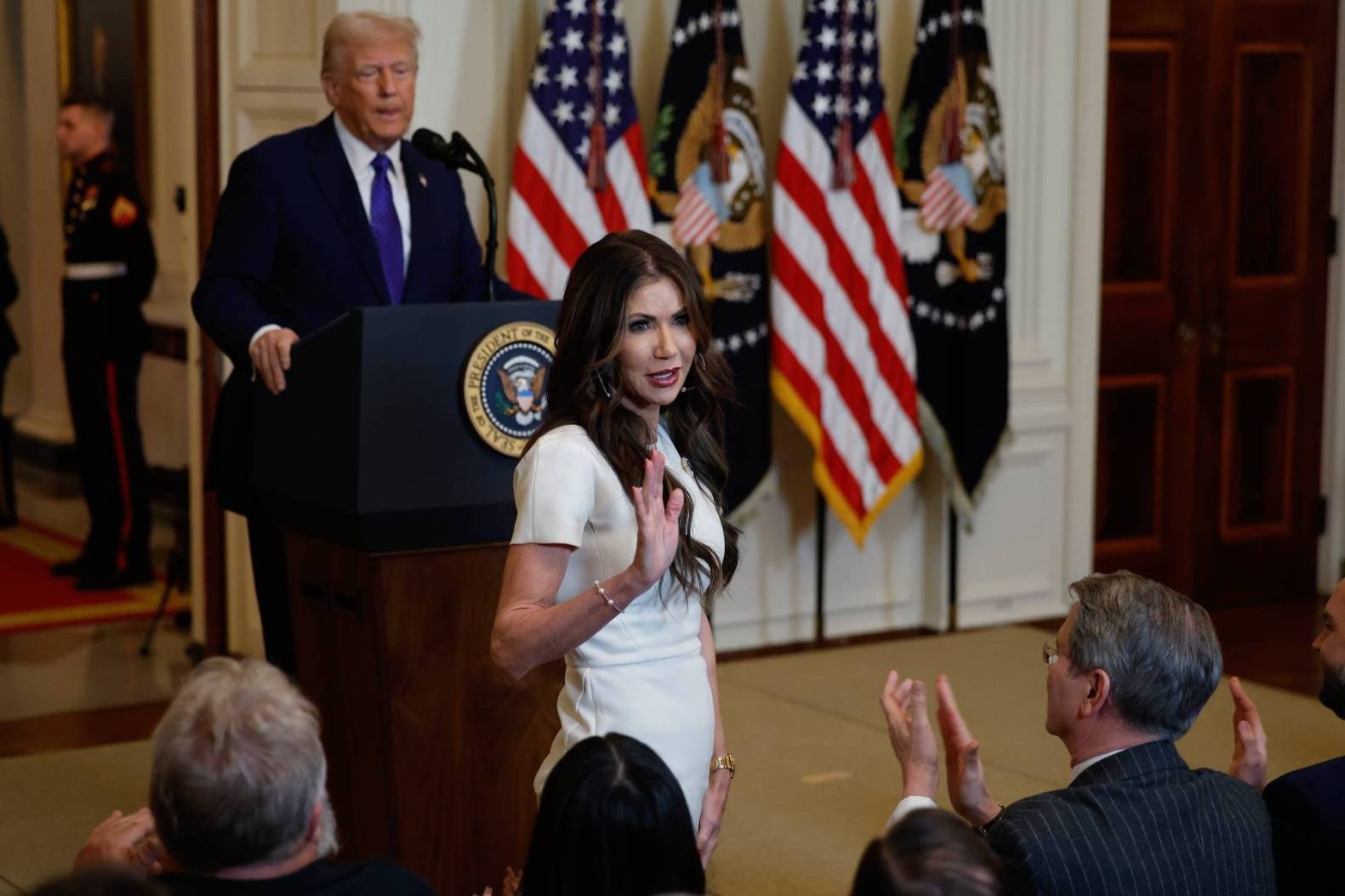 Kristi Noem stands in front of President Donald Trump during the signing ceremony for the Laken Riley Act on Jan. 29, 2025 in Washington, D.C.