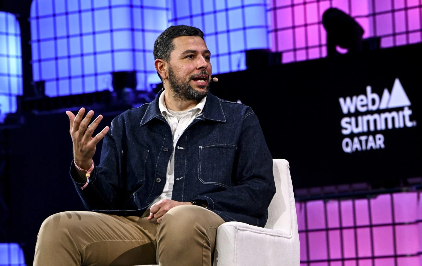 Ayman Mohyeldin gestures from his seat on the Web Summit Qatar 2024 stage.