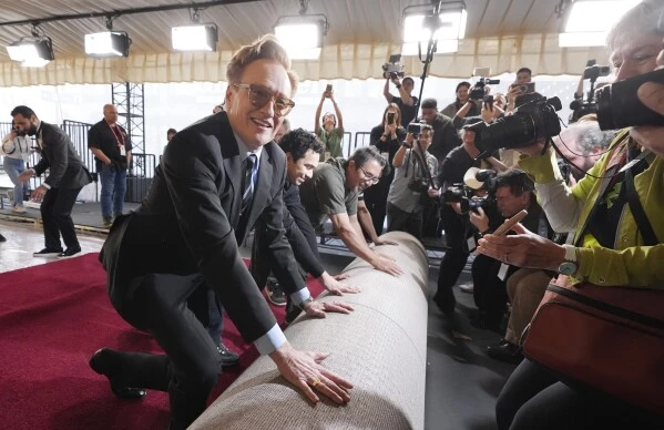 Conan O'Brien, host of Sunday's 97th Academy Awards, helps to roll out the red carpet for the show at the Dolby Theatre on Wednesday, Feb. 26, 2025, in Los Angeles. (AP Photo/Chris Pizzello)