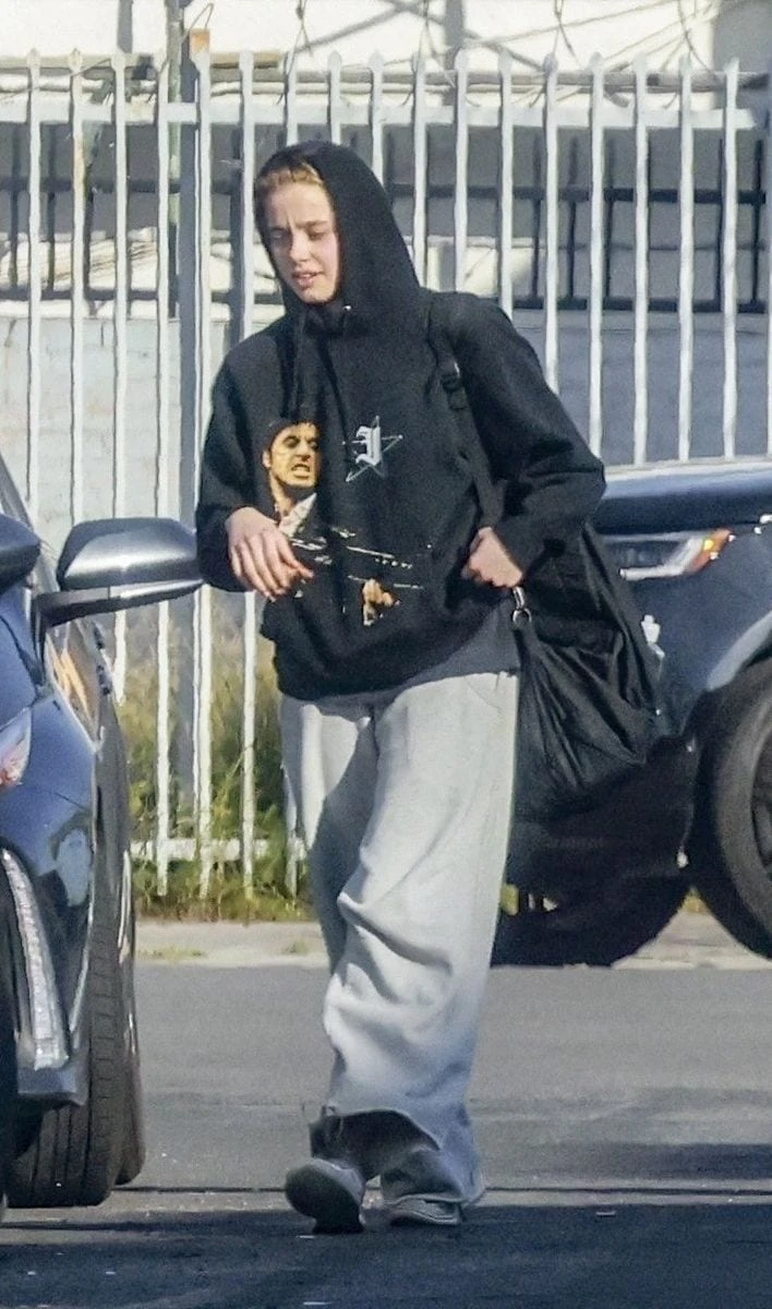 Shiloh Jolie was seen leaving a dance class, keeping a low profile in a black hoodie featuring a graphic print of a scene from Scarface, paired with oversized gray sweatpants making a casual and relaxed look.