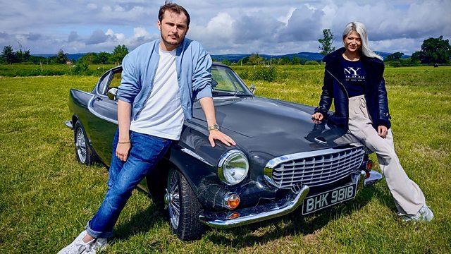 Two people posing with a vintage Volvo.