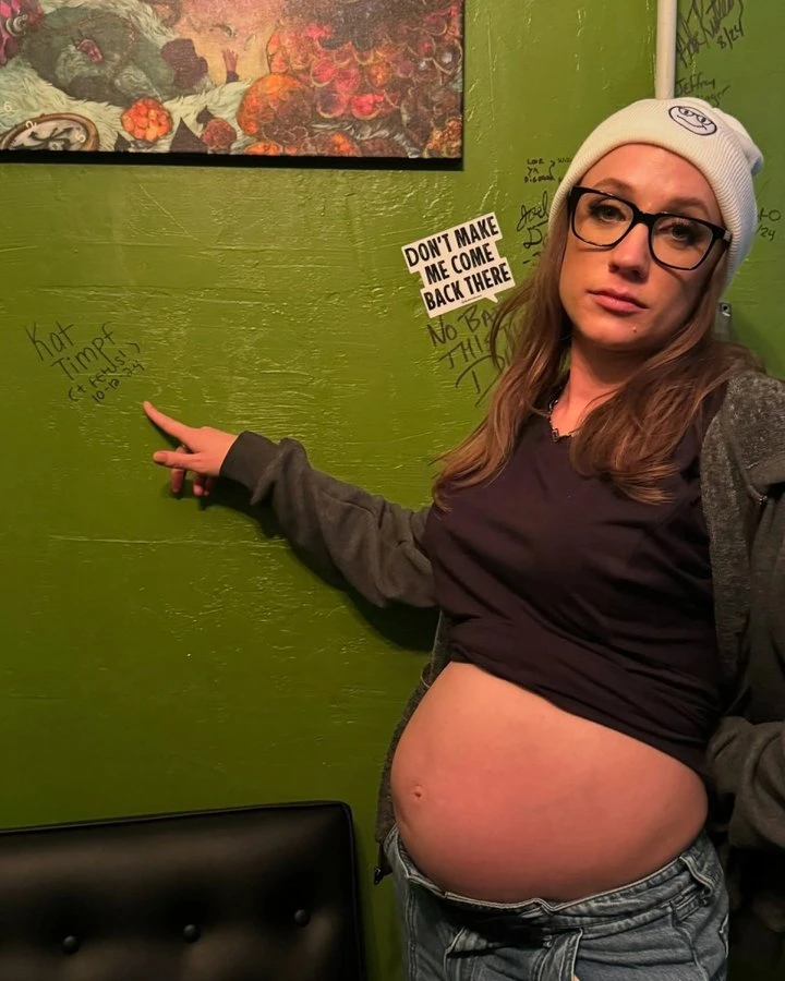 Katherine Timpf, Fox News star, pointing at a green wall while pregnant