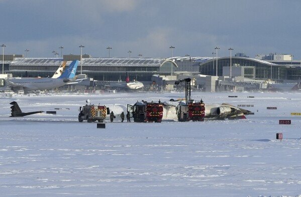 Pearson International Airport firefighters work on an upside down Delta Air Lines plane, which was heading from Minneapolis to Toronto when it crashed on the runway, in Toronto, Monday, Feb. 17, 2025. (Teresa Barbieri/The Canadian Press via AP)