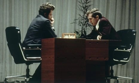 Two men in suit haunched over a desk during a chess game