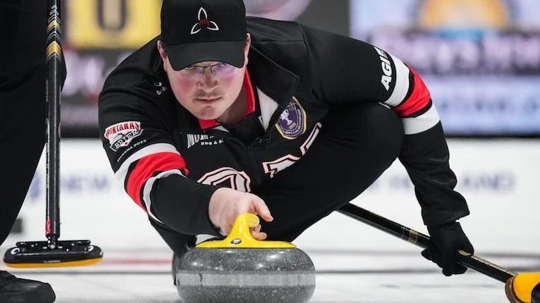 A male curler lunges down on ice to throw a curling rock.