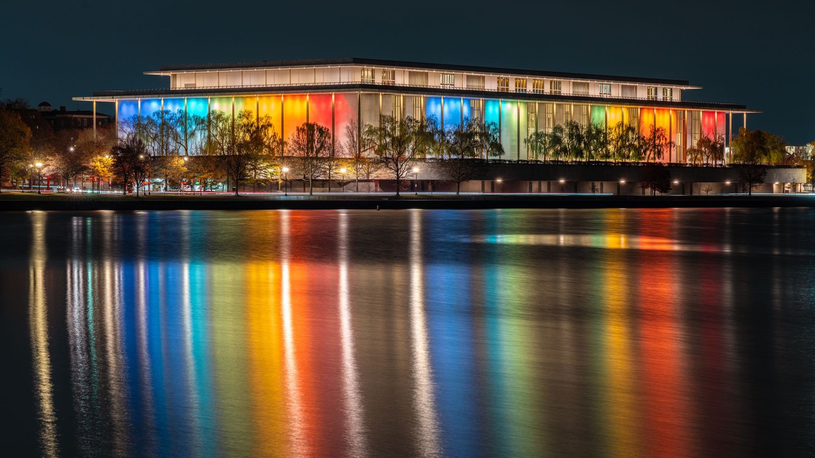 Reflected in the Potomac River, the exterior of the John F. Kennedy Center of the Performing Arts building is lit up in multiple colors in advance of the annual Kennedy Center Honors on December 1, 2024, in Washington, DC. (Photo by J. David Ake/Getty Images)