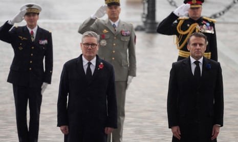 Keir Starmer and Emmanuel Macron, right, stand, arms by their sides, in front of saluting military chiefs.