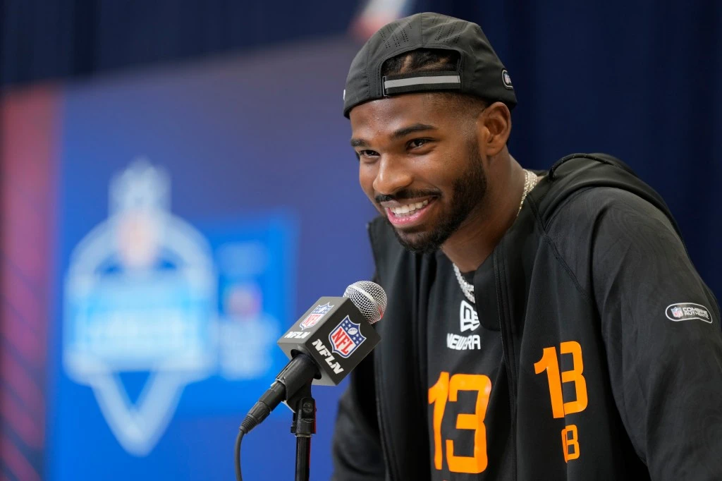 Shedeur Sanders, Colorado quarterback, speaking at a press conference during the NFL Scouting Combine on Feb. 28, 2025 in Indianapolis, wearing a black hat and jersey.