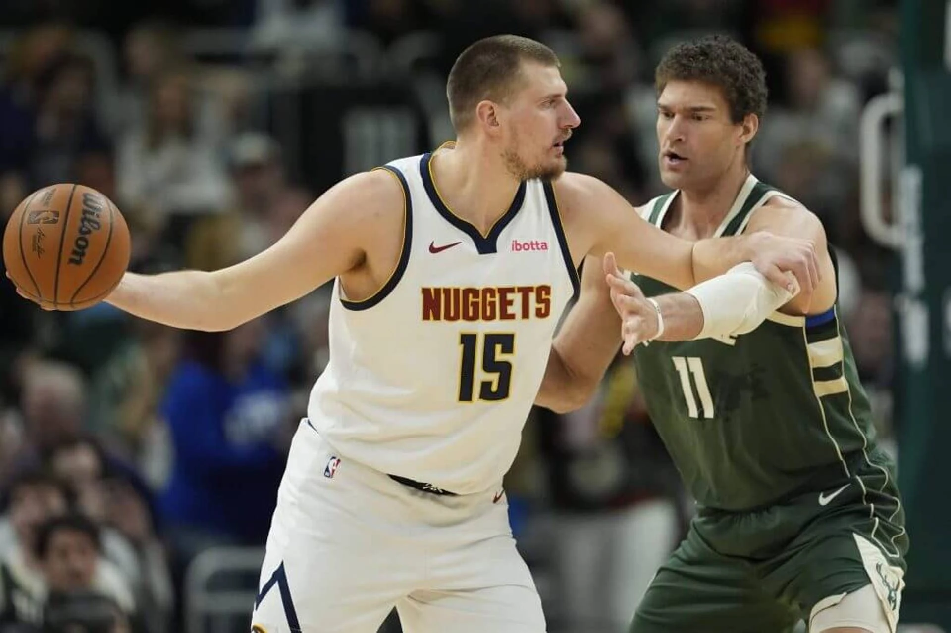 MILWAUKEE, WISCONSIN - FEBRUARY 27: Brook Lopez #11 of the Milwaukee Bucks defends against Nikola Jokic #15 of the Denver Nuggets during the first quarter at Fiserv Forum on February 27, 2025 in Milwaukee, Wisconsin.