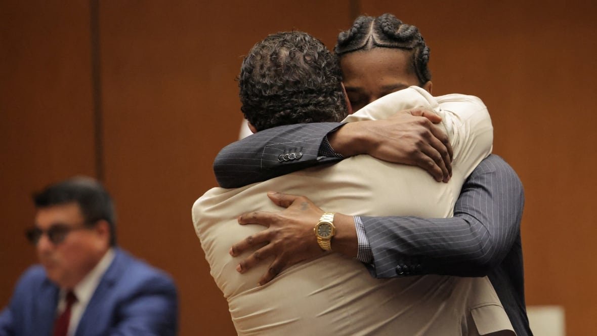 Two men in suits hug in a courtroom.