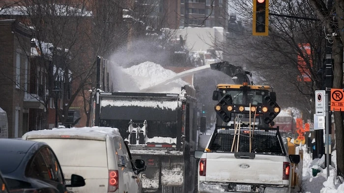 Des camions de déneigement au travail dans une rue de Montréal.