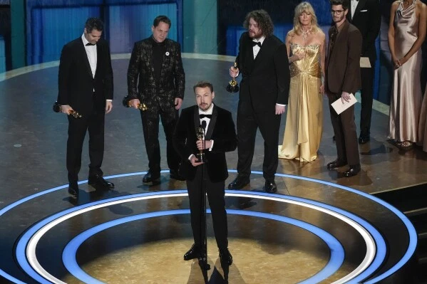 Gregory Zalcman, from left, Ron Dyens, Gints Zilbalodis, center, and Matiss Kaza accept the award for best animated feature film for "Flow" during the Oscars on Sunday, March 2, 2025, at the Dolby Theatre in Los Angeles. Goldie Hawn, second right, and Andrew Garfield look on from right.