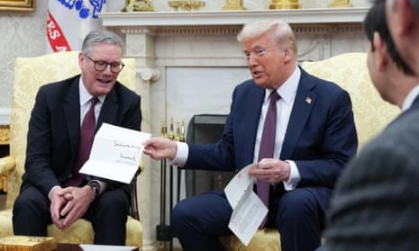 Donald Trump shows off an invitation from King Charles for a state visit to the UK during a meeting with Keir Starmer in the Oval Office of the White House.