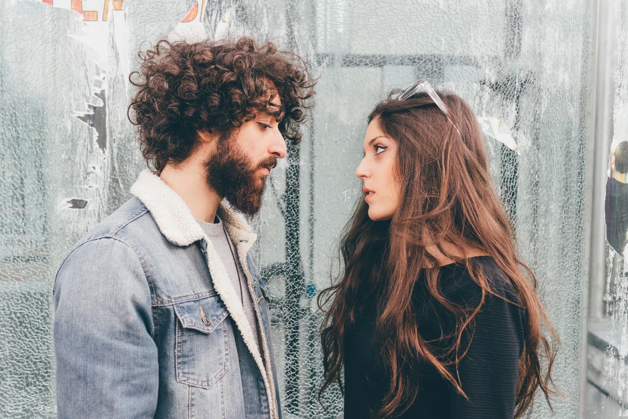 Young man and woman, standing face to face, pensive expressions.