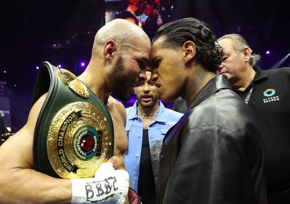 Two boxers facing each other, one holding a championship belt.