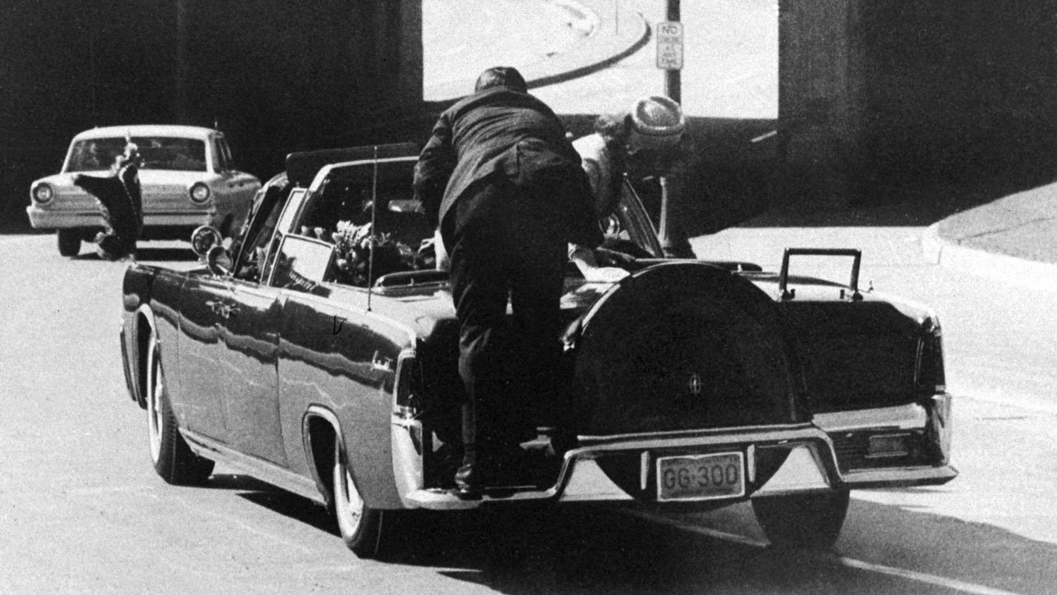 Secret Service Agent Clint Hill rides on the back of the presidential limousine after President John F. Kennedy was fatally shot in Dallas, Texas, on November 22, 1963. First lady Jacqueline Kennedy leans over the president.