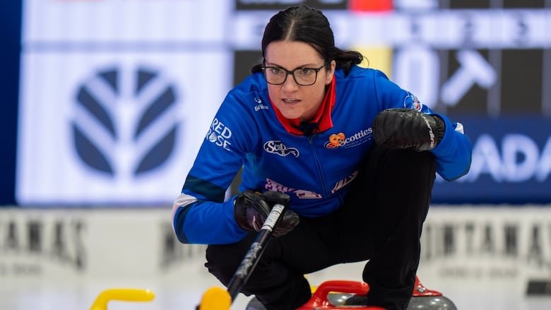 A female curler delivers a rock.