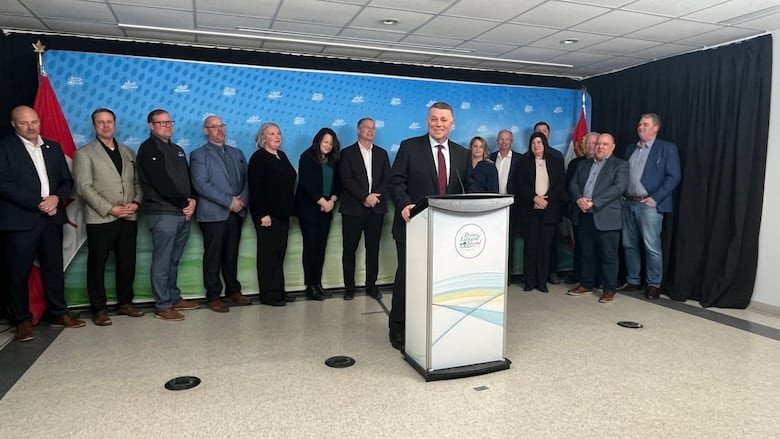 Man in suit stands aat podium