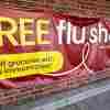 This photo shows a wide banner advertising free flu shots. It hangs on a brick wall.